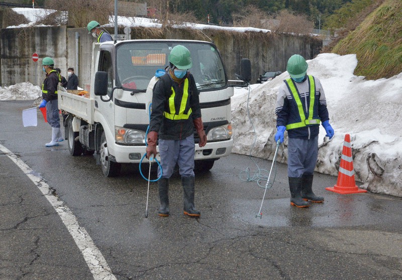ため池に近い県道を消毒する作業員=津幡町倉見で2021年1月26日午前10時19分、阿部弘賢撮影