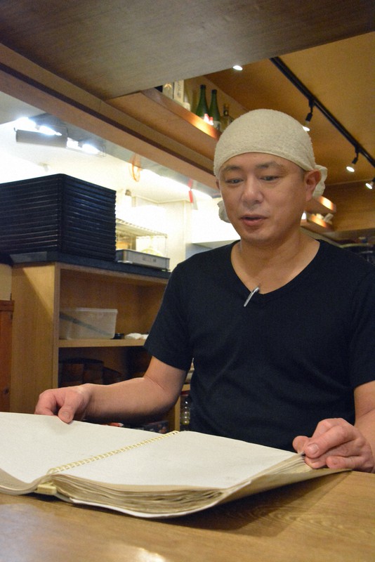 ほぼ空白となった予約帳を手にする海鮮居酒屋「快海」店主の石居弘司さん=東京都中央区で2021年1月26日午後7時過ぎ、高橋祐貴撮影