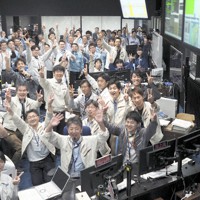 探査機「はやぶさ2」が小惑星リュウグウへの2回目の着陸を成功させたことを喜ぶ管制室の運用メンバーたち。細田聡史・JAXA主任研究開発員の提案で、皆でVサインを出した＝相模原市中央区のJAXA宇宙科学研究所管制室内で2019年7月11日午前10時50分、宇宙科学研究所/JAXA提供