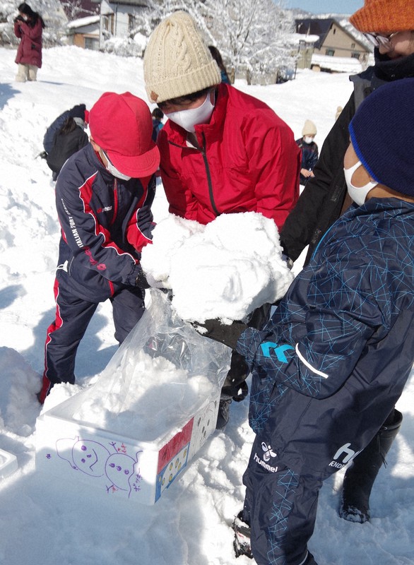容器に校庭の雪を詰める児童=新潟県南魚沼市立六日町小学校で1日、新井敦撮影