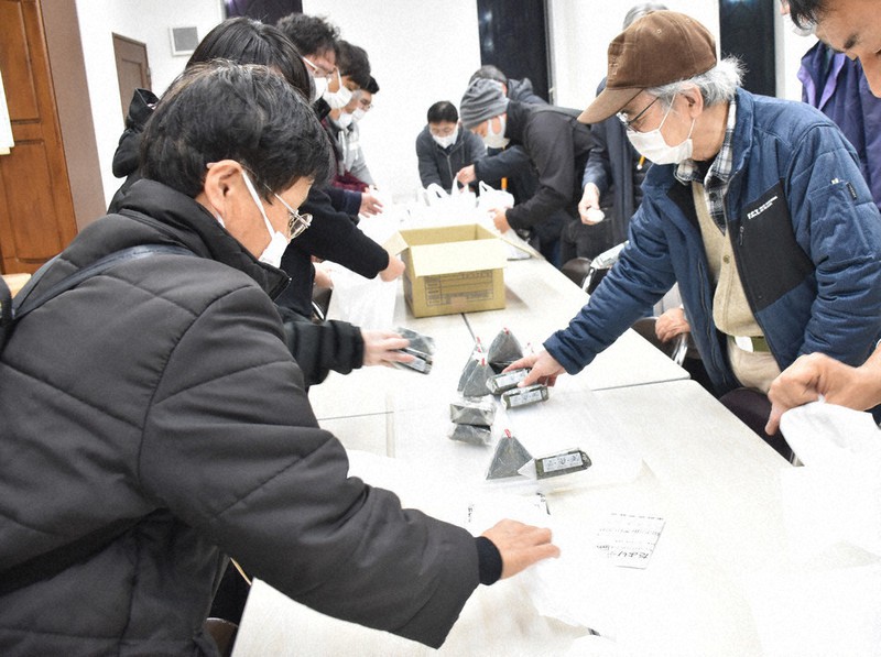 支援物資のおにぎりを袋に詰めるボランティア