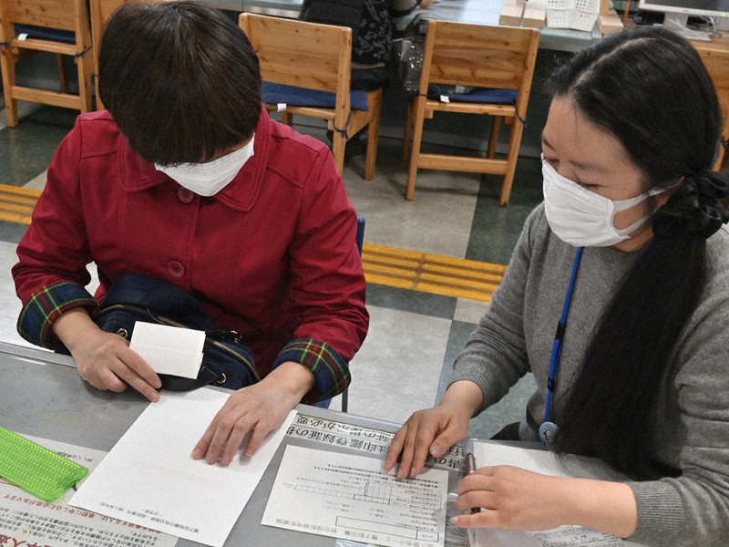 職員から暗証番号設定に関する説明に受ける栗田さん(左)