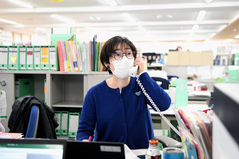 発熱患者からの電話を受けて張り紙を見上げ、紹介できる医療機関を探す新井久子係長=東京都港区のみなと保健所で2021年1月25日、竹内紀臣撮影