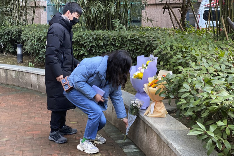 新型コロナウイルスで亡くなった武漢市の医師、李文亮さんが勤務していた病院を訪れ、花を手向ける市民=中国湖北省で2021年2月6日、AP