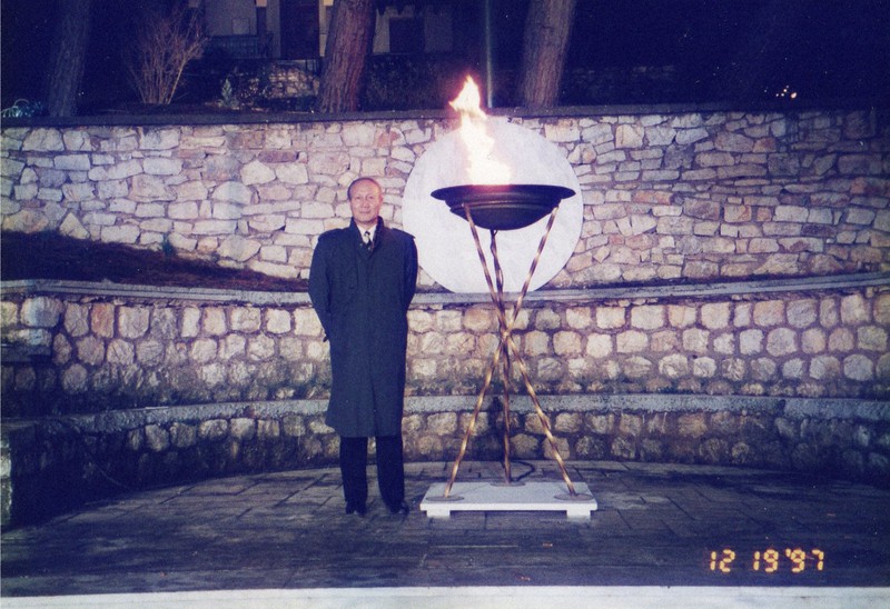 ギリシャで採火された聖火を背景に記念撮影する笠原一也さん=ギリシャで1997年12月19日(笠原さん提供)