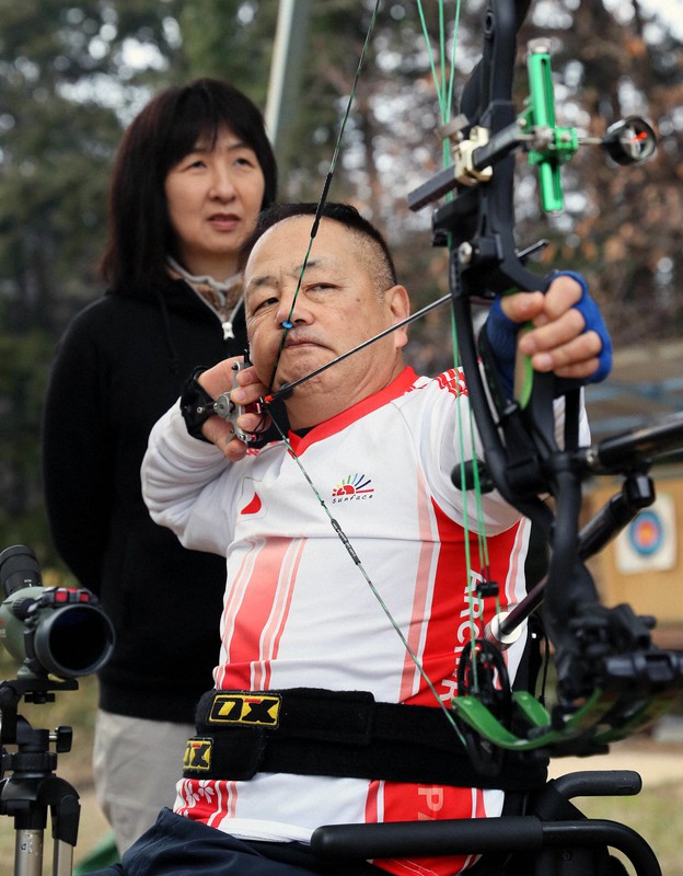 妻奈生美さん(奥)とともに練習するパラアーチェリーの仲喜嗣さん=奈良県桜井市で2020年2月15日、幾島健太郎撮影