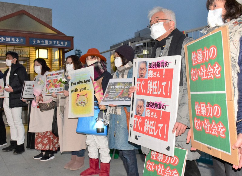 プラカードや花を手にしてフラワーデモをする参加者ら=熊本市中央区で2021年2月11日午後6時8分、栗栖由喜撮影