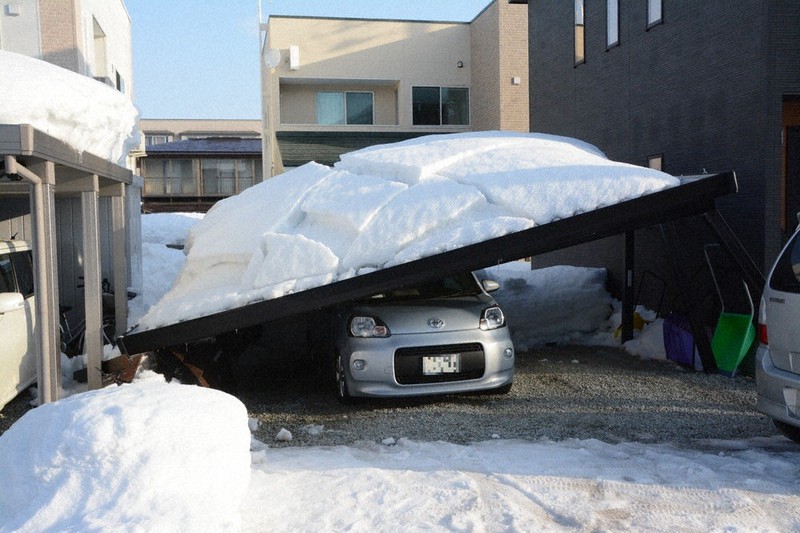 倒壊したカーポートの下敷きになった乗用車=山形県米沢市堀川町で2021年2月14日午前7時55分、佐藤良一撮影(画像の一部を加工しています)