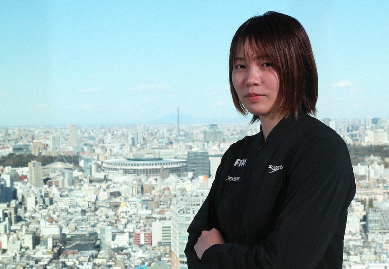 コロナ下での東京オリンピックについて自身の考えを語った競泳の松本弥生選手。奥は国立競技場=東京都渋谷区で2021年2月9日、長谷川直亮撮影