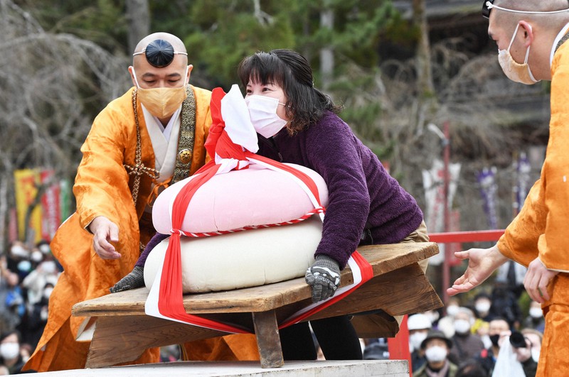 「餅上げ力奉納」で紅白の鏡餅に挑む女性=京都市伏見区の醍醐寺で2021年2月23日午後0時36分、山崎一輝撮影