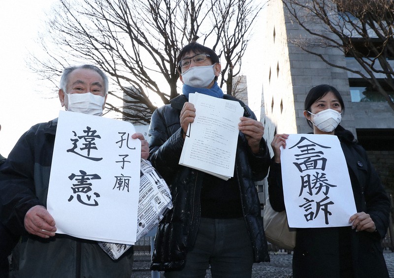 那覇市の孔子廟を巡る政教分離訴訟の上告審判決を受け「違憲」「全面勝訴」などと書かれた紙を掲げる原告の代理人弁護士ら=最高裁前で2021年2月24日午後3時37分、玉城達郎撮影