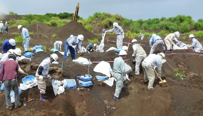 硫黄島・自衛隊の滑走路西の遺骨収容現場。遺骨とともにさまざまな遺品や兵器が見つかった。手前左端が筆者（栗原俊雄）＝2012年7月11日撮影、厚生労働省提供