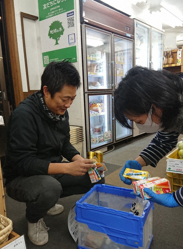 フードドライブ活動に協力する津田稔也さん(左)=八王子市東浅川町の自然食品販売店「地球の木」で