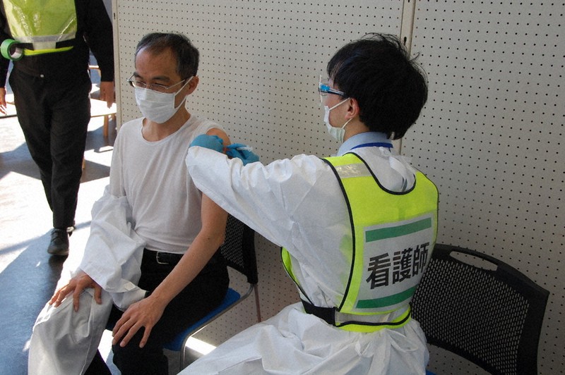 高齢者役の市職員(左)の腕に「ワクチン接種」に見立てて注射器を当てる看護師役=群馬県の渋川市民会館で2021年2月24日、庄司哲也撮影