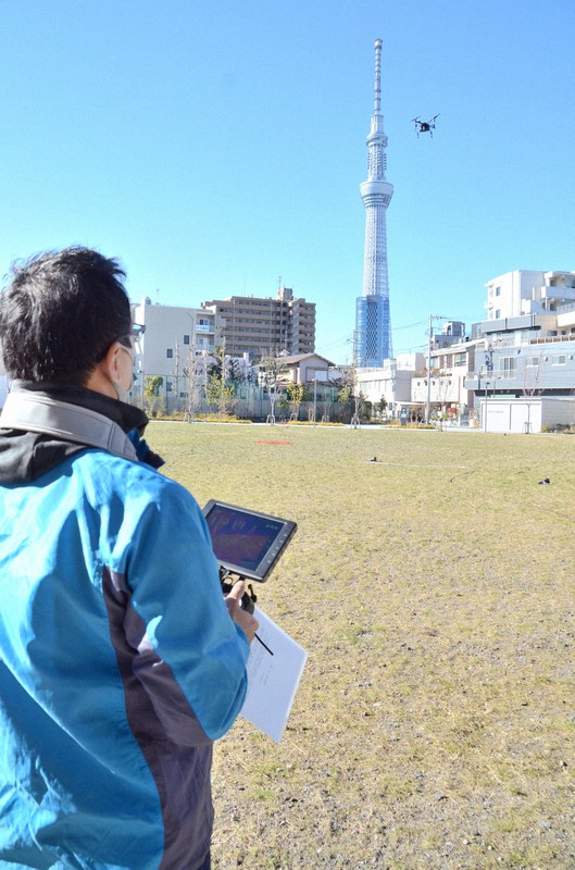 ドローンを飛ばし、周囲の住宅を撮影するスタッフ=東京都墨田区のiU情報経営イノベーション専門職大学で2020年12月21日午前10時58分、竹内麻子撮影