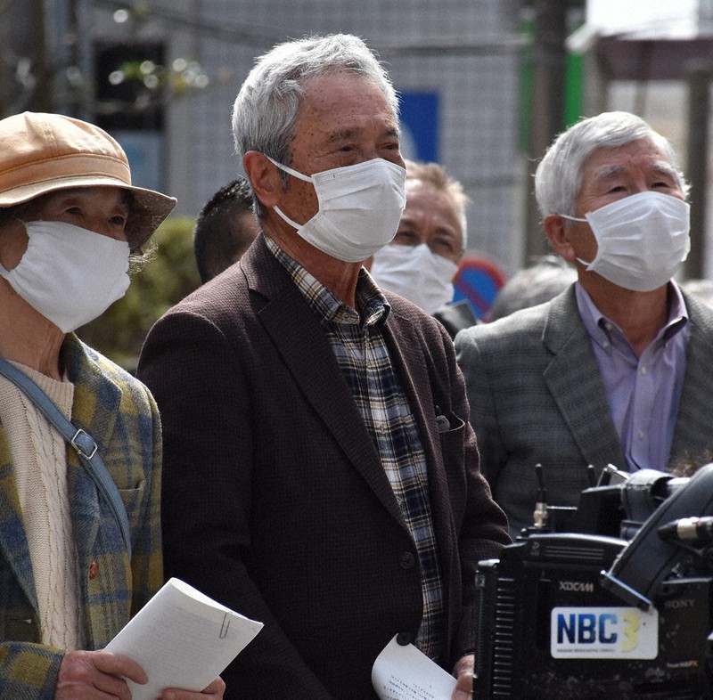 長崎地裁前での集会に参加した原告の奥村さん(中央)