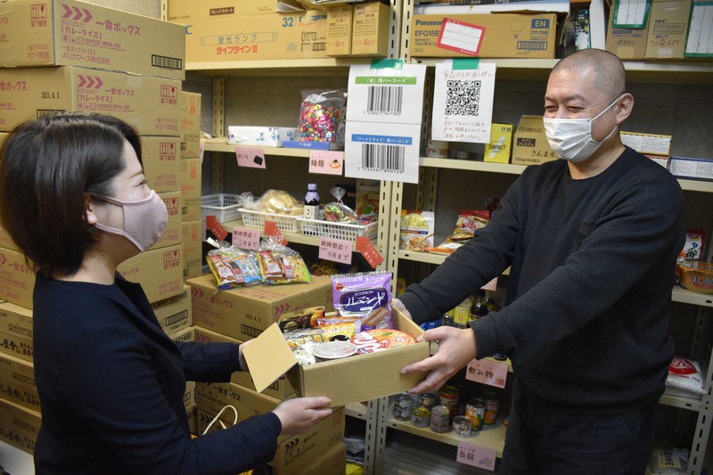 会社で集まった食品を「フードバンクびわ湖」の曽田俊弘理事長(右)に手渡す、パソナ滋賀支店の高井杏菜さん=滋賀県守山市吉身2の同法人食品保管庫で2021年3月1日午後3時22分、小西雄介撮影
