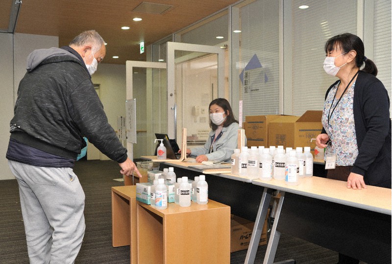 新型コロナウイルス対策で群馬県高崎市が配布するエタノールを受け取る市民(左)=同市提供