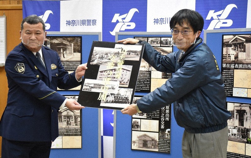 神奈川県警山手署の前田俊明署長(左)から交番写真のパネルを受け取る横浜市八聖殿郷土資料館の相澤竜次館長=同署で2021年3月2日、宮島麻実撮影
