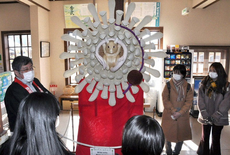 食品で作られた飾り物「ダシ」の展示を前に、学生らに左義長まつりについて説明する保存会の安田晴彦さん(左端)=滋賀県近江八幡市為心町元の白雲館で2021年3月3日午前10時0分、村瀬優子撮影