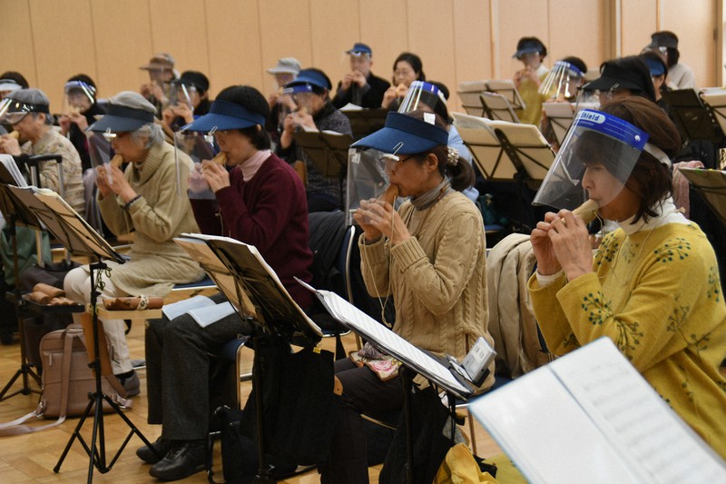 フェースシールドを装着し、「奇跡の一本松」で作ったコカリナで定期演奏会の練習に励む「東京コカリナアンサンブル」のメンバー=東京都江東区の区文化センターで2021年3月4日午後3時10分、川村咲平撮影