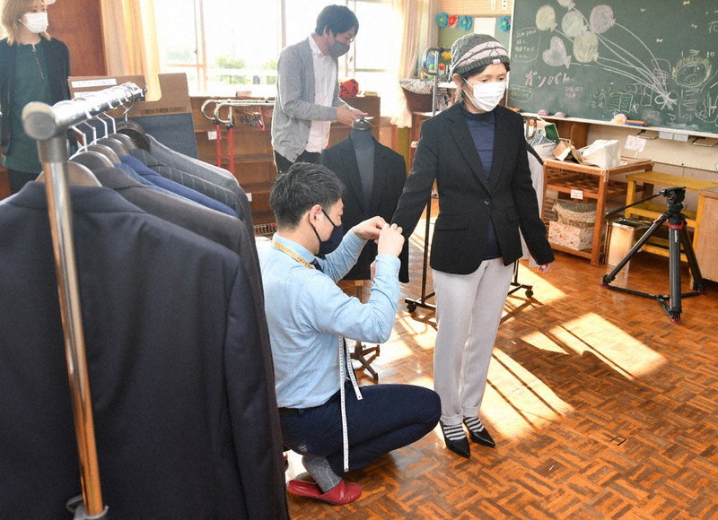 ジャケットのサイズを調整してもらう保育園の職員
