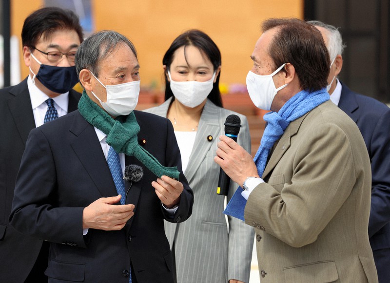 JR双葉駅を視察し、伊沢史朗双葉町長(右)からタオルマフラーを贈られた菅義偉首相=福島県双葉町で2021年3月6日午前10時58分(代表撮影)