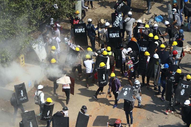 6日、ミャンマーの最大都市ヤンゴン郊外で、治安部隊が放った催涙ガスから逃れるデモ隊=AP