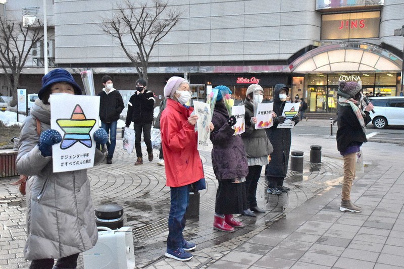 花を片手に性暴力の根絶を訴えるフラワーデモの参加者ら=青森市の青森駅前公園で2021年3月8日、平家勇大撮影