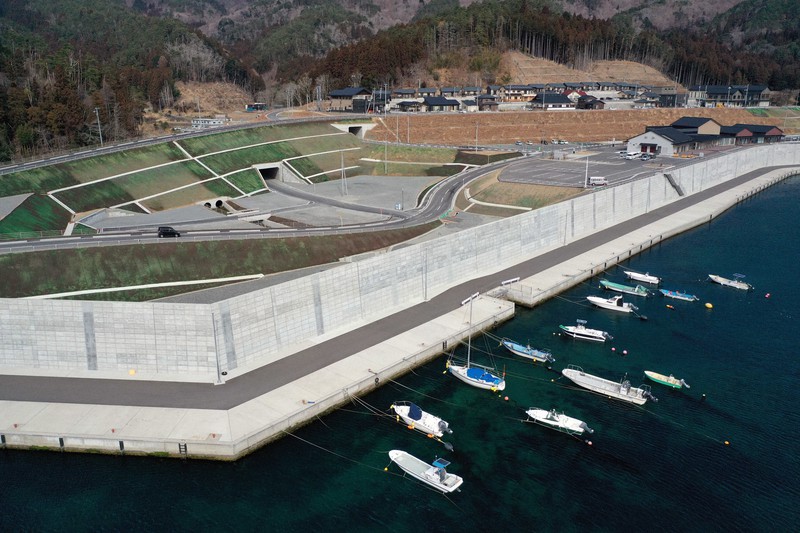 海岸線に沿って建設された防潮堤。右奥は高台に造成された住宅地=宮城県石巻市雄勝町で2021年2月26日、小型無人機で小川昌宏撮影