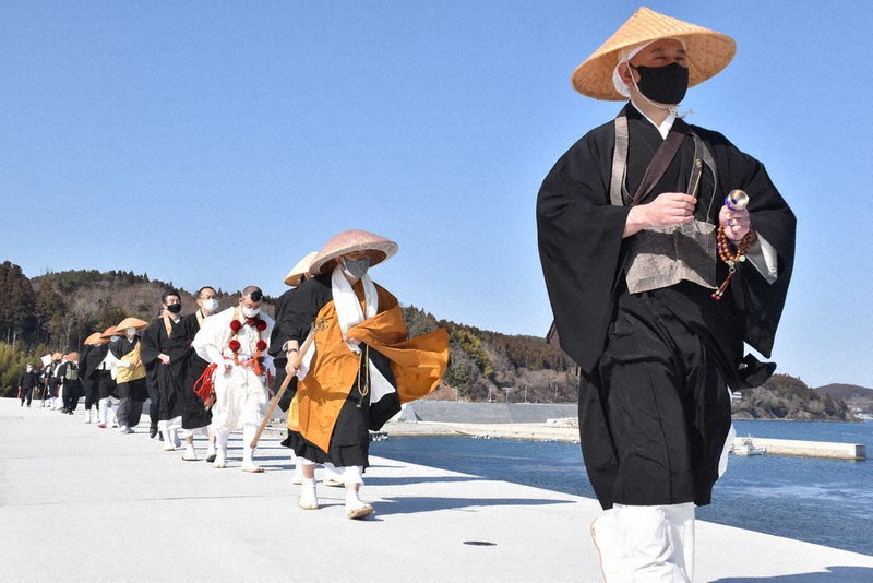 防潮堤の上を歩きながら祈りをささげる追悼行脚の参加者=宮城県南三陸町戸倉で2021年3月9日、滝沢一誠撮影