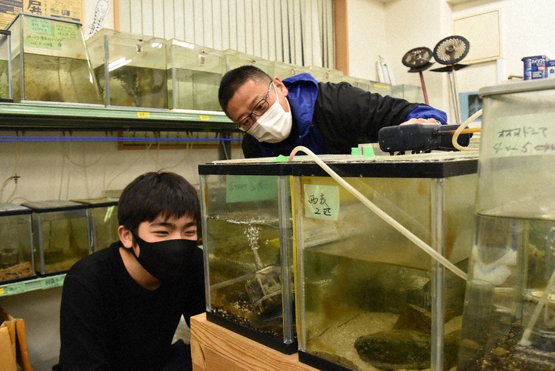 多くの水槽が並ぶ「基地」で、生き物の様子について話すNPO法人北九州・魚部の井上理事長(右)と伊藤さん