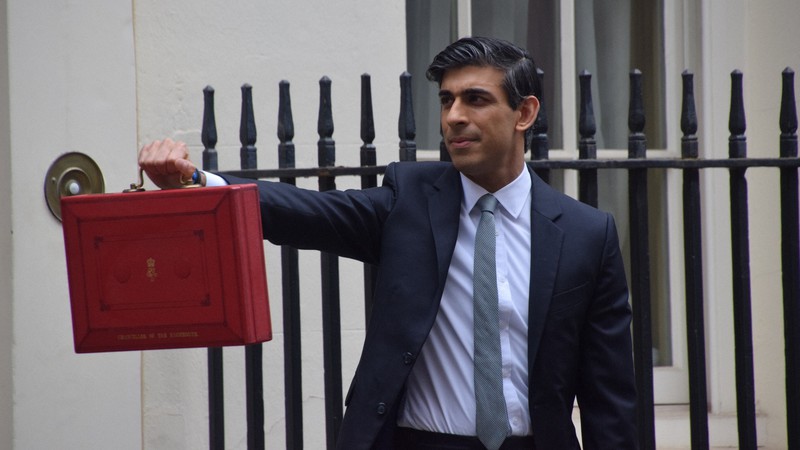予算案の入った赤い箱を手に報道陣の前に登場した英国のスナク財務相=ロンドンで2021年3月3日、横山三加子撮影