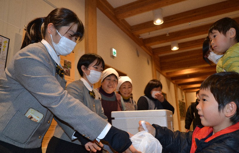 子ども食堂「おしゃっち食堂」で町内の子どもたちにお弁当を手渡す中村有沙さん(左)=岩手県大槌町末広町で