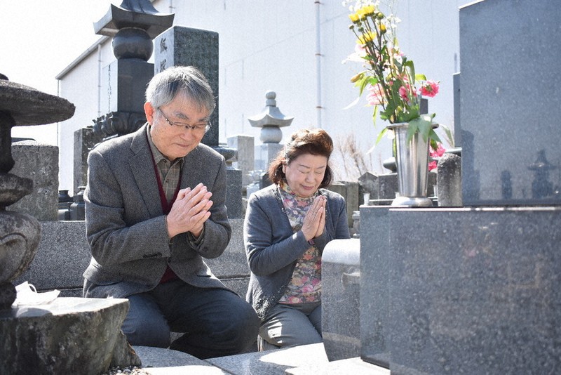 坂村正子さんの墓標に手を合わせる長男倍男さん(左)と倍男さんの妻芳子さん=館林市で2021年3月11日、鈴木敦子撮影