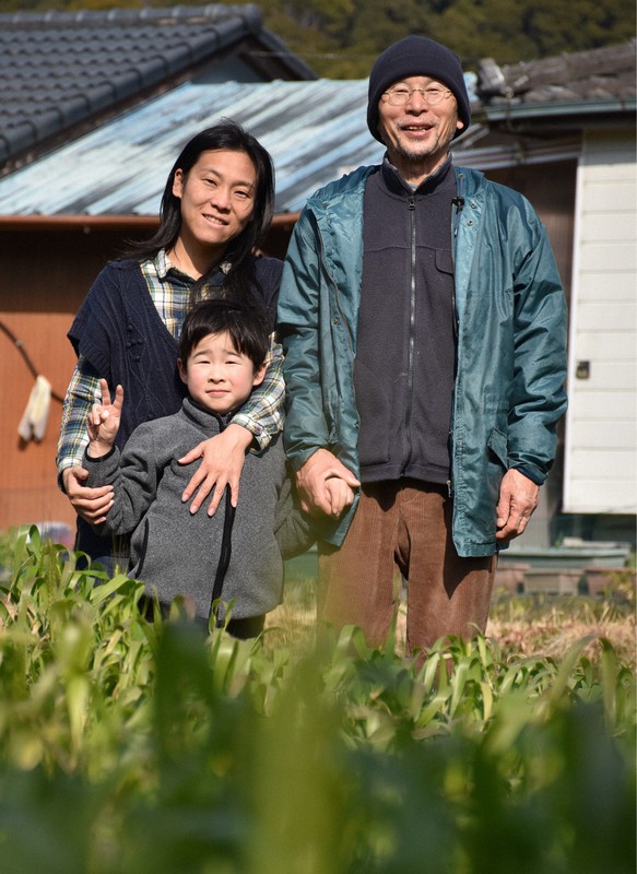麦畑を前に笑顔を見せる佐々木義秋さん(右)、妻奈津子さん、長男新之助さん=和歌山県日高川町で2021年2月7日午後1時32分、木原真希撮影