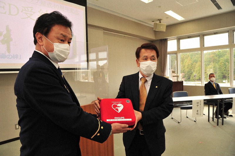 水口学消防長(左)にAEDを贈呈する田中秀明会長=京都府福知山市東羽合町の市消防防災センターで、佐藤孝治撮影