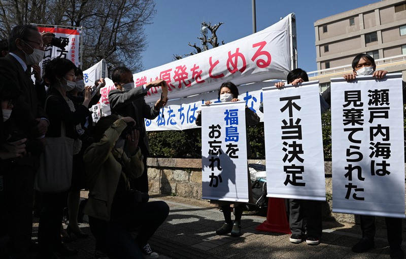 広島高裁の決定を受けて、「不当決定」などと書かれた垂れ幕を掲げる住民側の関係者=広島市中区で2021年3月18日午後2時4分、望月亮一撮影