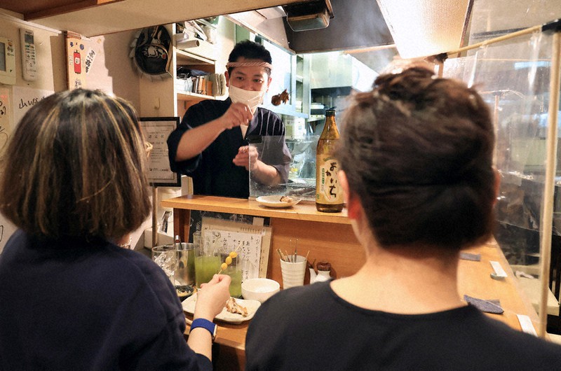 接客をする焼き鳥店「山しな」の山科昌彦さん(中央)=東京都港区で18日午後7時5分、梅村直承撮影