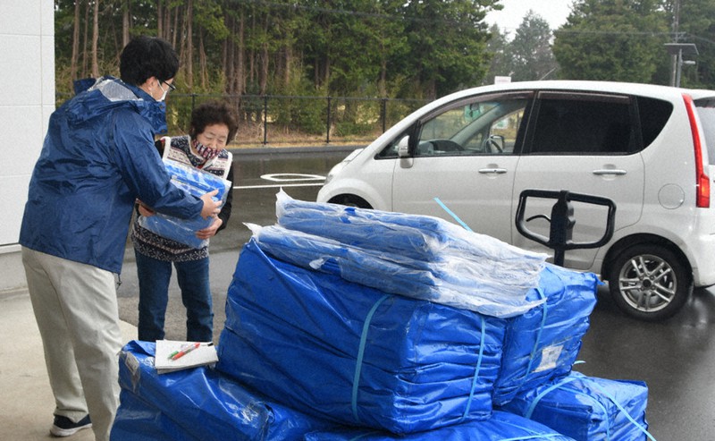 震度5弱の地震の後、雨に備えてブルーシートを受け取る住民=福島県南相馬市原町区の防災備蓄倉庫で2021年3月21日、高橋秀郎撮影