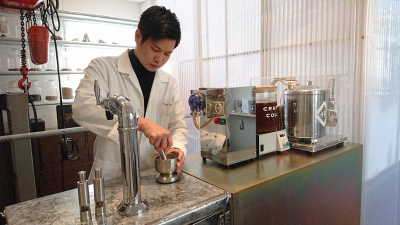 工房の中でスパイスの実をすりつぶす作業をする小林さん。右はコーラシロップ＝東京都新宿区で3月24日、賀川智子撮影