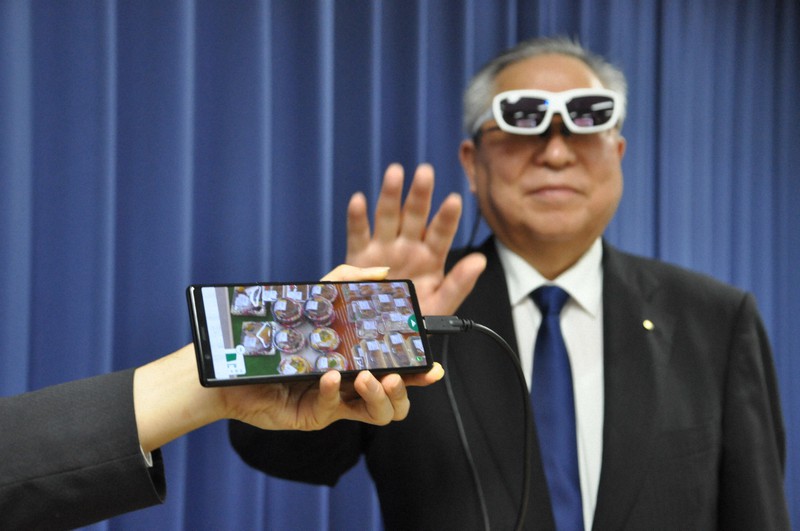 VRグラスに映った商品に手を伸ばす門馬和夫・南相馬市長=福島県南相馬市役所で2021年3月24日午後2時35分、高橋隆輔撮影