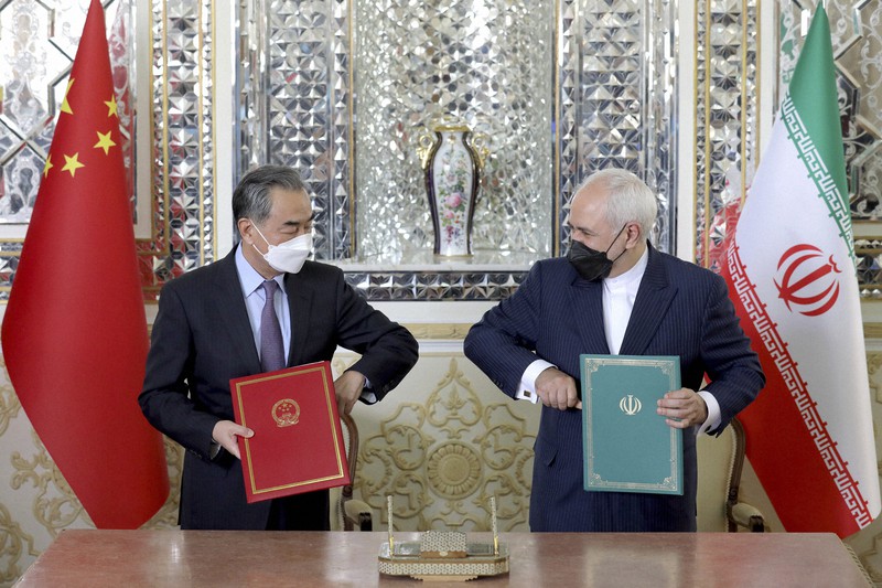 包括的戦略パートナーシップ協定に署名した後、肘タッチの格好をするイランのザリフ外相(右)と中国の王毅国務委員兼外相=テヘランで2021年3月27日、AP