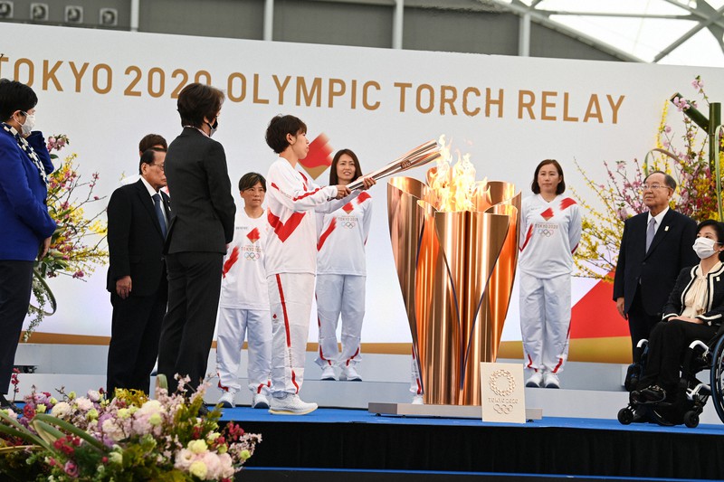 東京オリンピックの聖火リレー出発式で、トーチに火をともすサッカー女子ワールドカップ・ドイツ大会で優勝した日本代表「なでしこジャパン」のメンバーら=福島県楢葉町のJヴィレッジで25日(代表撮影)