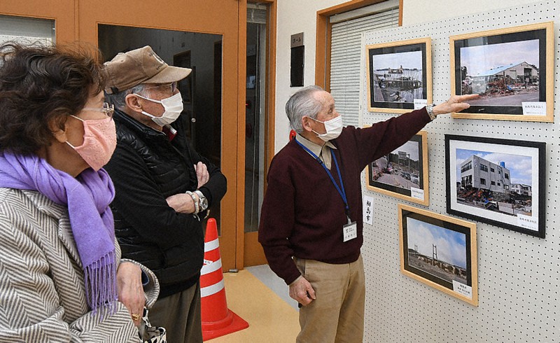 東日本大震災の写真を来場者に説明する大槻明生さん(右)=福島県南相馬市原町区の「道の駅南相馬」で2021年3月20日、高橋秀郎撮影