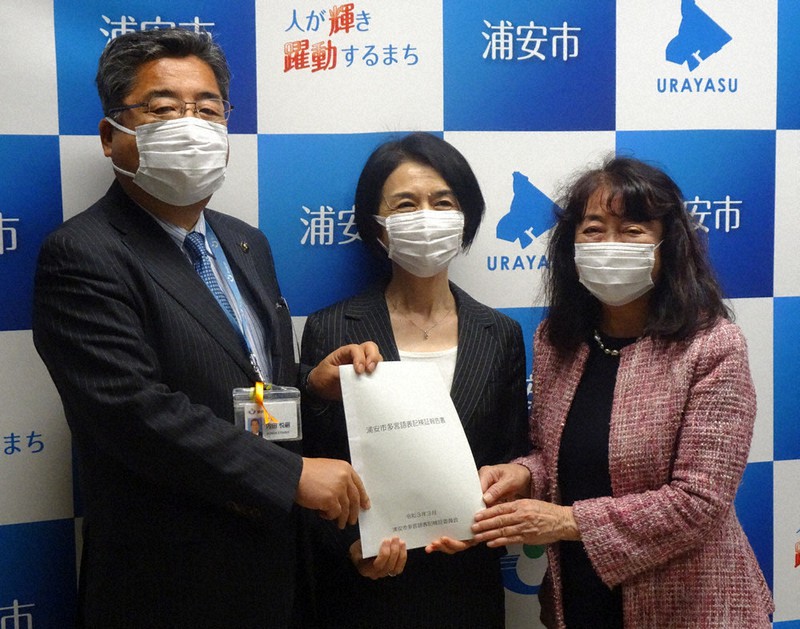 内田悦嗣市長(左)に報告書を提出する上杉恵美委員長(中央)と白木聖代副委員長=千葉県浦安市役所で2021年3月29日、小林多美子撮影