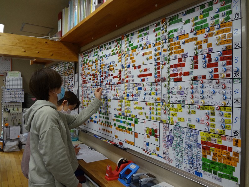 ホワイトボードにびっしりと埋まった訪問介護のスケジュールを確認する埼玉県新座市のNPO法人「暮らしネット・えん」のスタッフ=「えん」提供