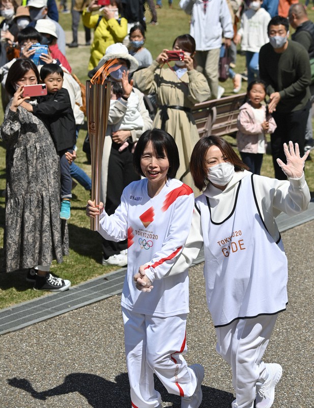 トーチを手に鈴鹿青少年の森を走る黒田智子さん(左)=三重県鈴鹿市で2021年4月7日午前11時2分、兵藤公治撮影
