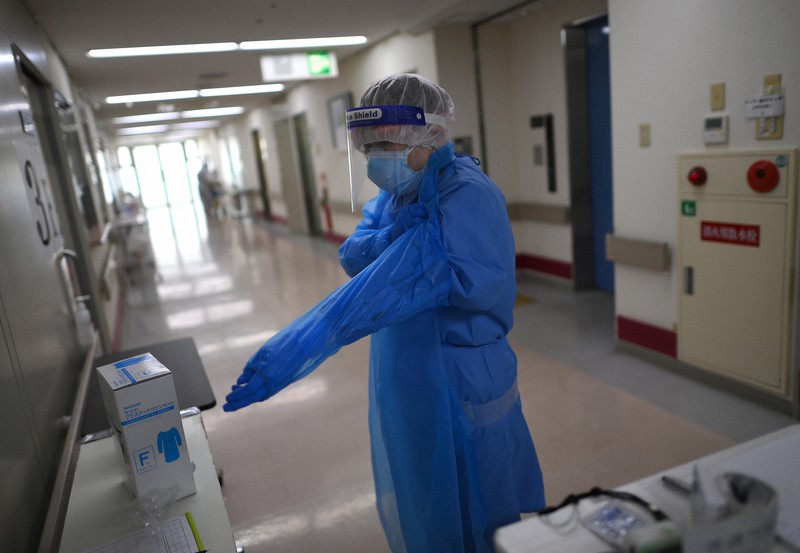 変異株患者の対応のため、病室に入る前に防護服の上からさらにガウンを着る看護師=大阪市住吉区の阪和第二病院で2021年4月3日、久保玲撮影