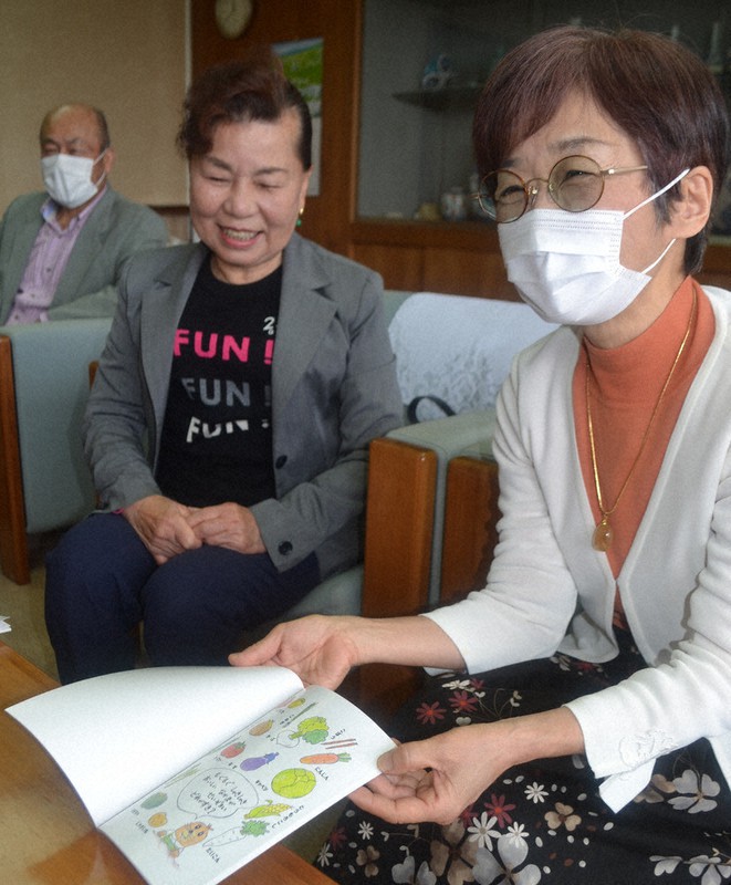 伊万里市役所で深浦弘信市長に絵本「モグモグちゃん」を開いて説明する竹内さん(右)と岩永さん